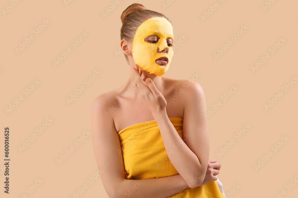 Young woman with turmeric sheet mask on beige background