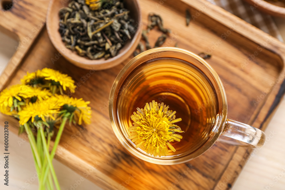 Board with bowl and glass cup of healthy dandelion tea on white wooden background