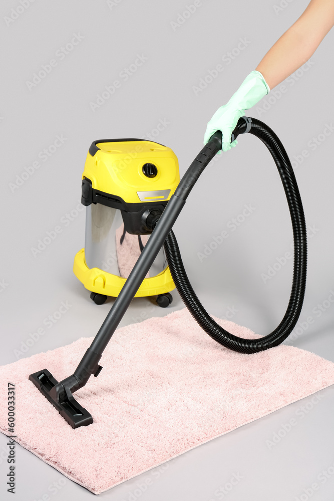 Woman hoovering carpet on grey background