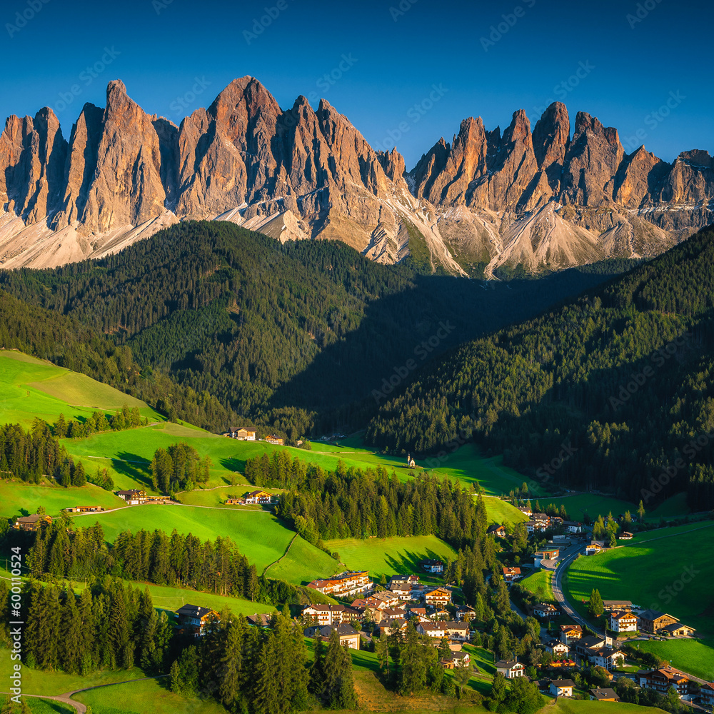 Charming alpine village with green fields and mountains, Dolomites, Italy