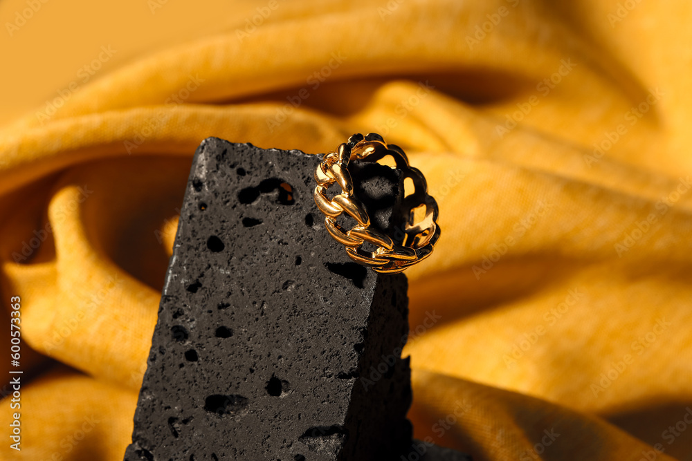 Decorative podium with beautiful ring on yellow fabric background