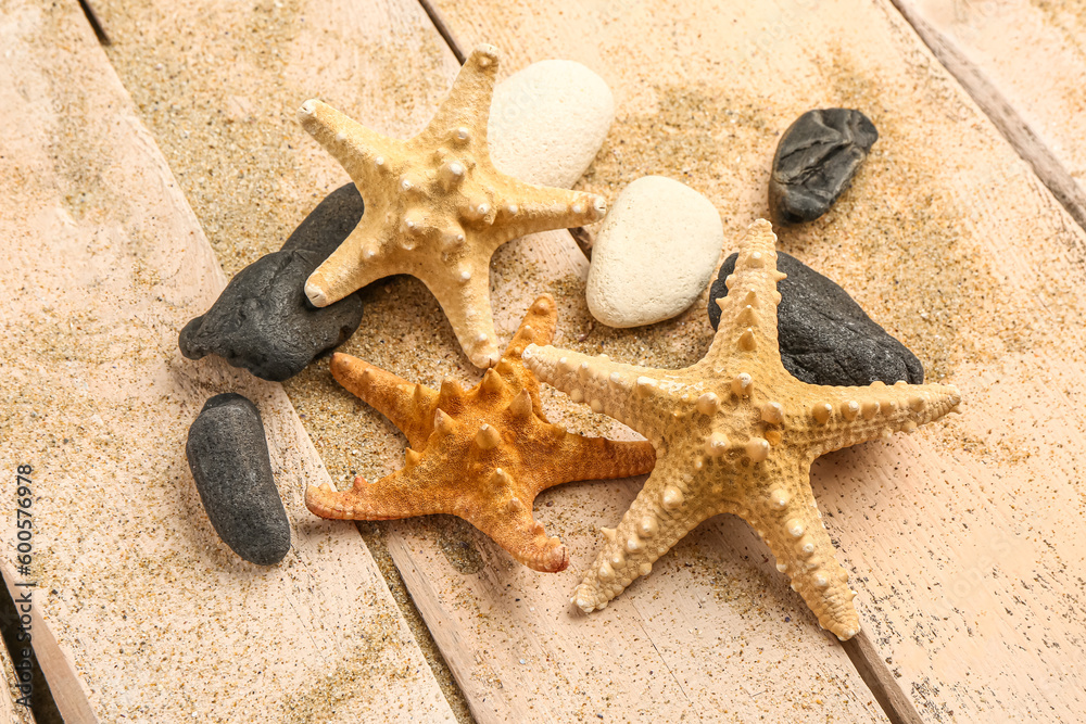 Sand with starfishes and shells on beige wooden background