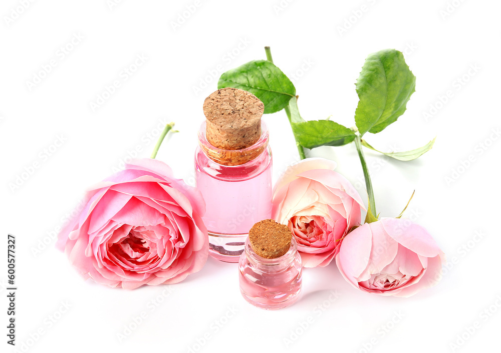 Bottles of cosmetic oil with rose extract and flowers on white background