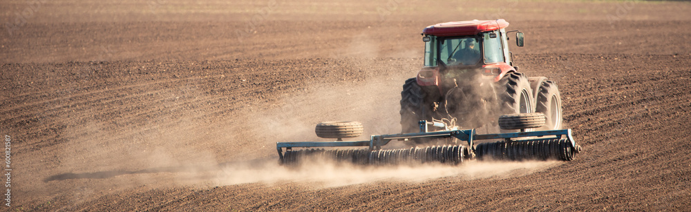 Farm tractor working the land with cultivator attachment