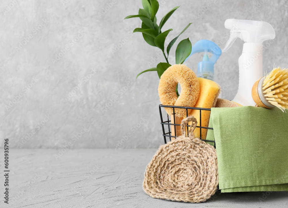 Basket with set of natural cleaning supplies on grey background, closeup