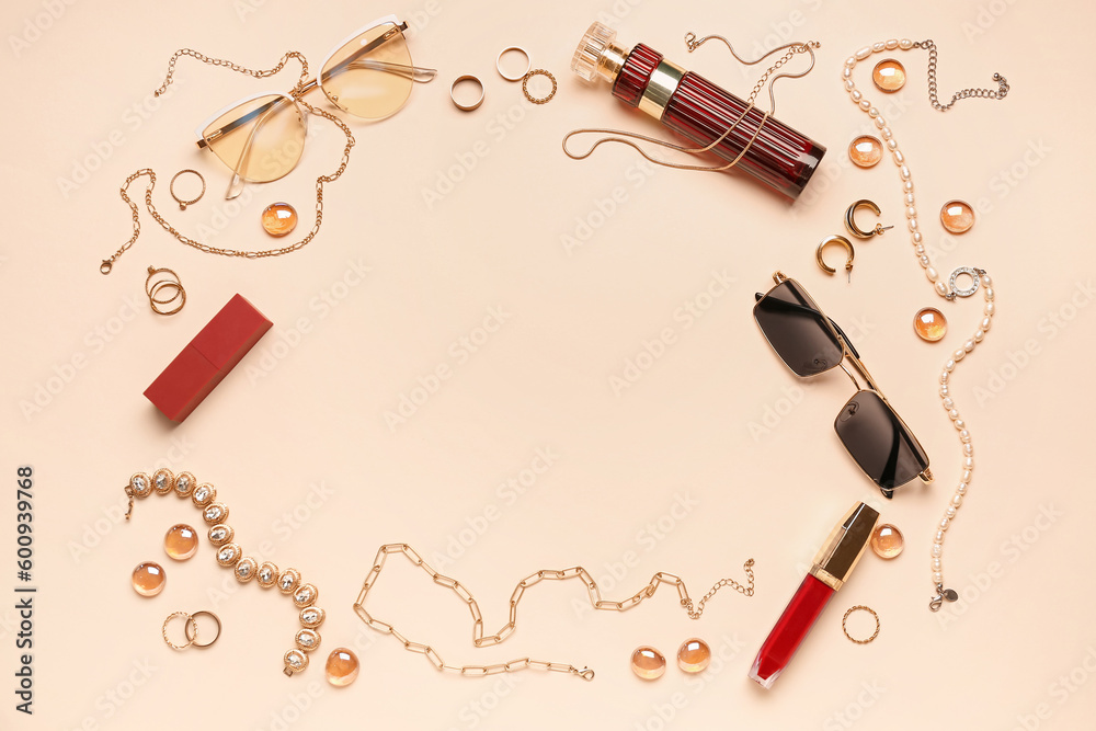 Frame made of sunglasses, jewelry and lipsticks on beige background