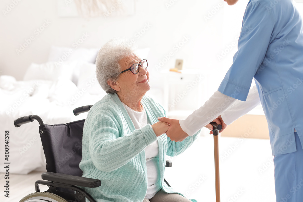 Senior woman in wheelchair with caregiver at home