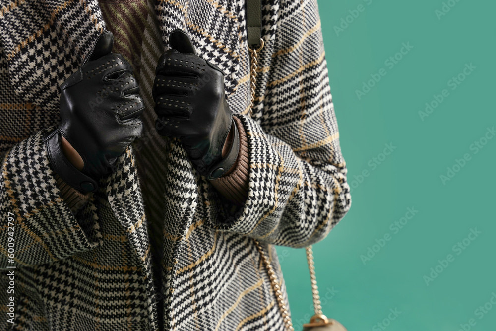 Beautiful woman in leather gloves and coat on green background, closeup