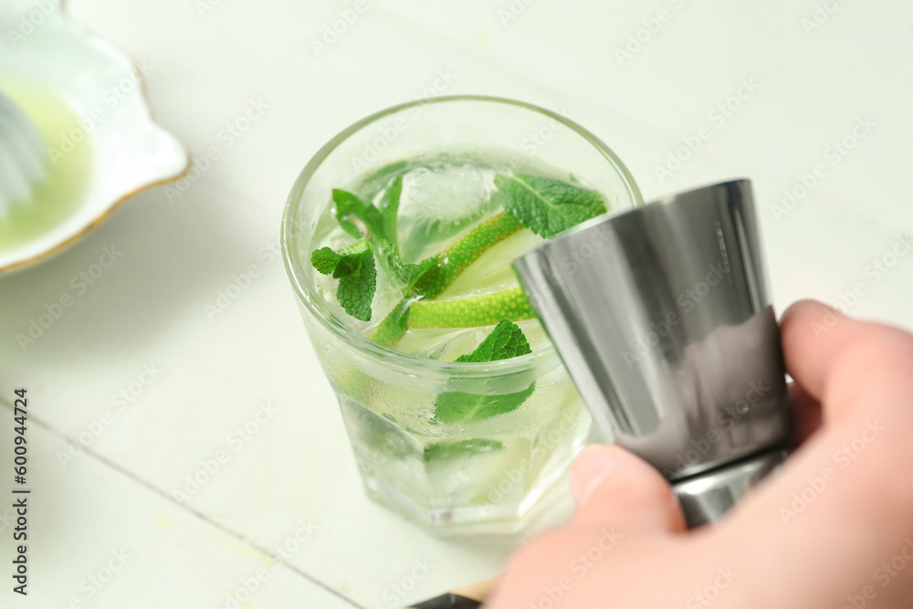 Female bartender making tasty mojito cocktail on white table