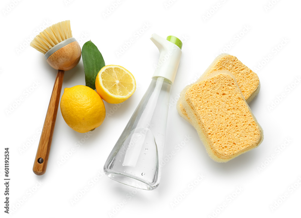 Bottle of vinegar, sponges, brush and lemons on white background