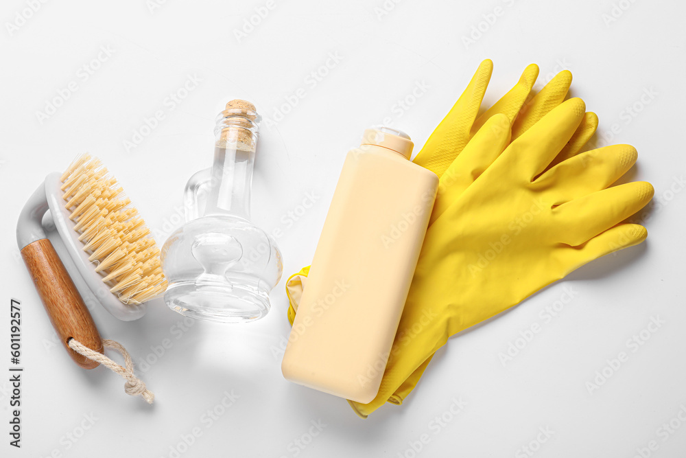 Decanter of vinegar, detergent, brush and rubber gloves on white background