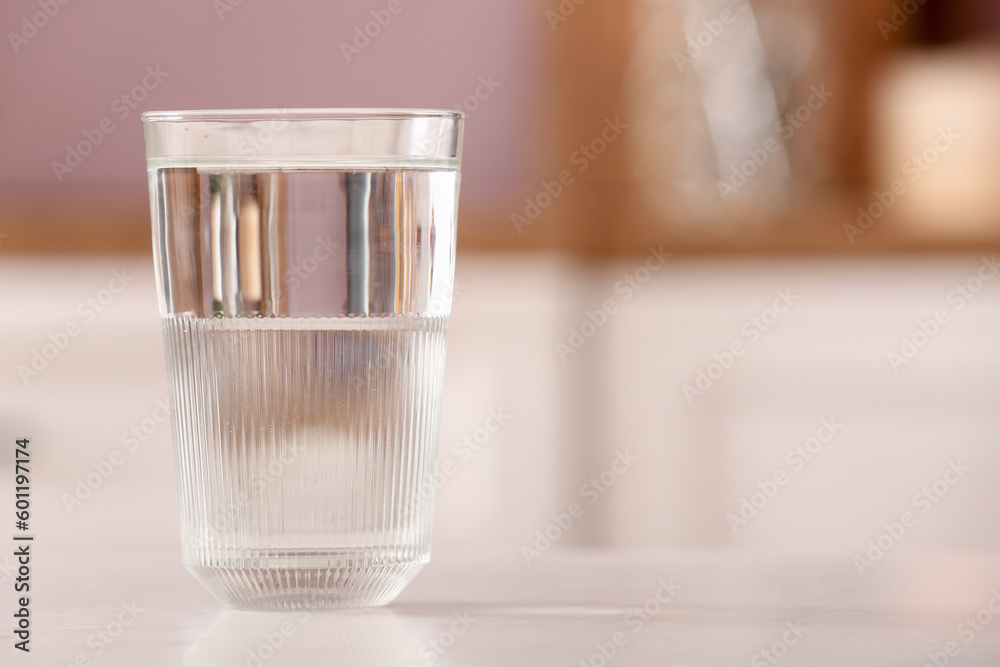 Glass of filtered water on table in kitchen, closeup