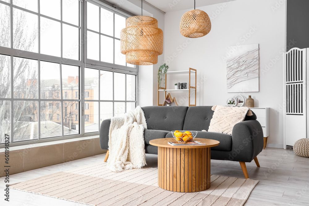 Interior of bright living room with cozy sofa and coffee table near big window