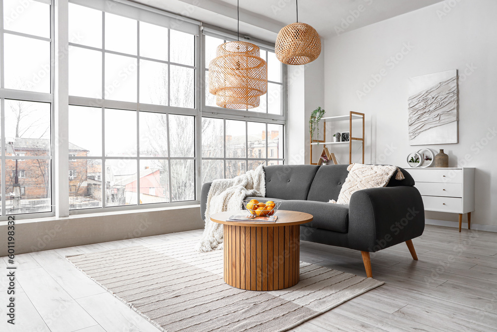 Interior of bright living room with cozy sofa and coffee table near big window