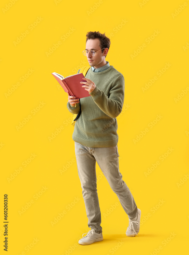 Male student with book on yellow background