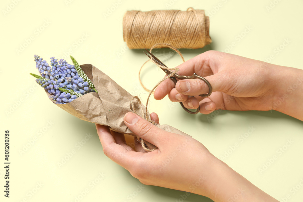 Woman making bouquet from beautiful Muscari flowers on beige background