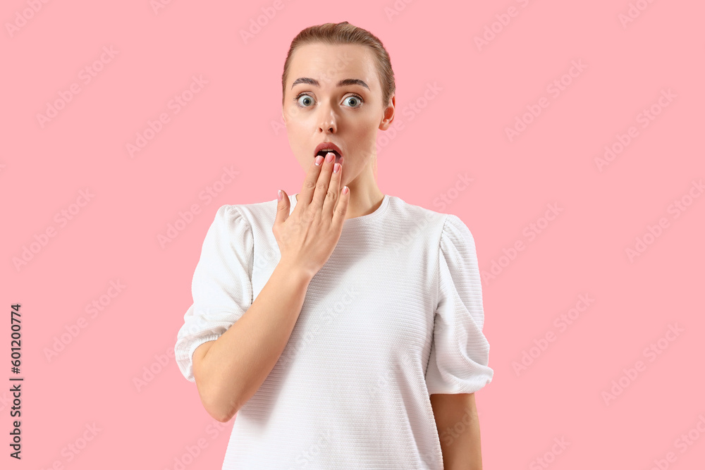 Shocked young woman on pink background