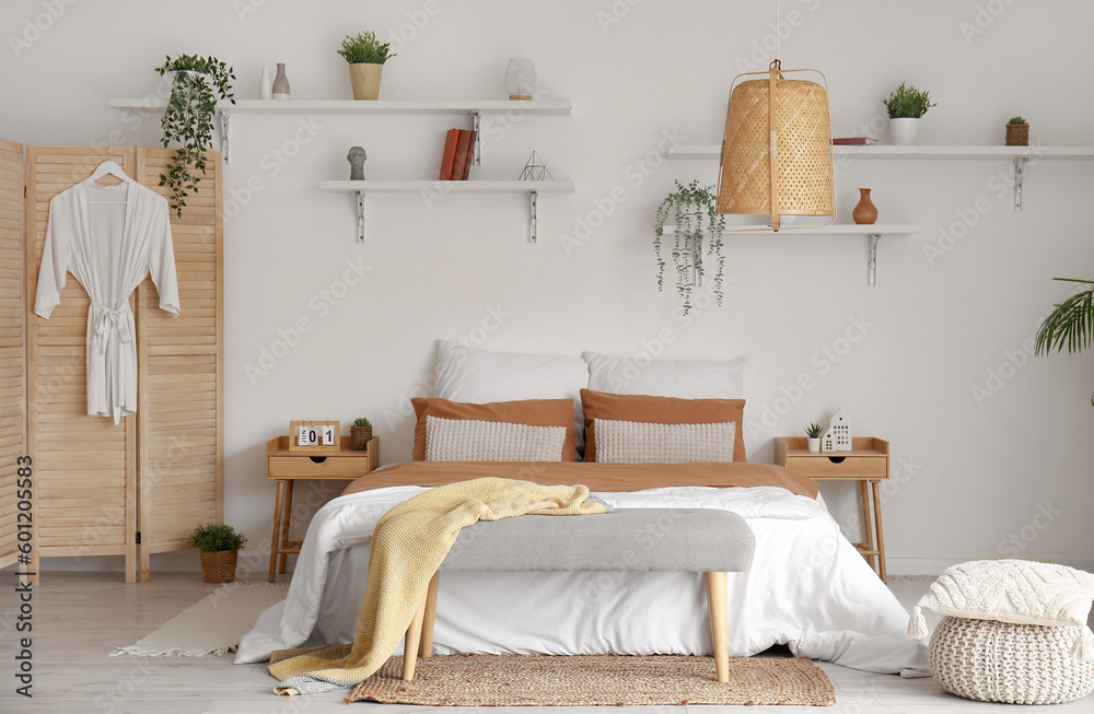 Interior of stylish bedroom with bed and houseplants on shelves