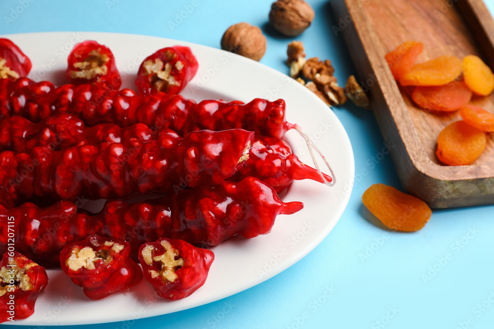 Plate with tasty churchkhela on blue background, closeup