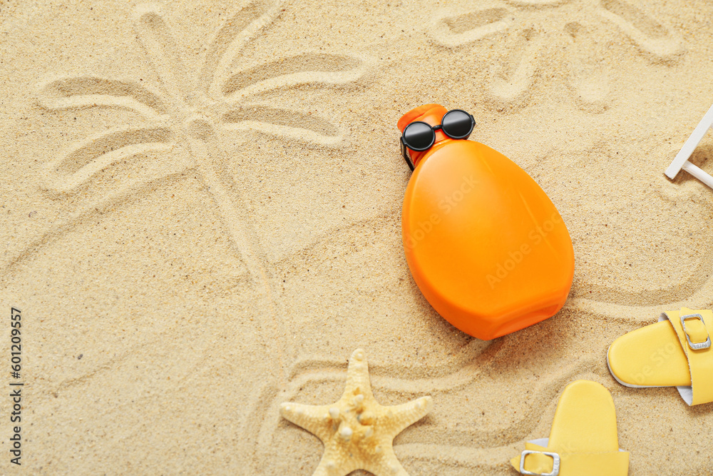 Creative composition with sunscreen cream, sunglasses and flip flops on sand