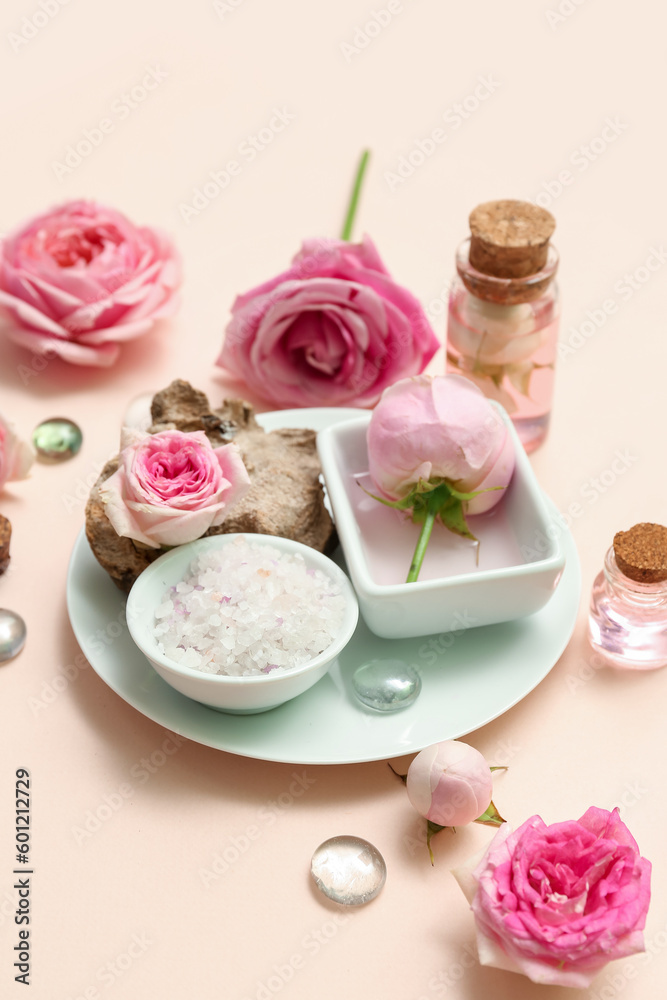 Bottles of cosmetic oil with rose extract and flowers on beige background