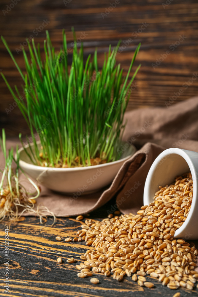 Bowl with fresh wheatgrass and kitchen towel on brown wooden table