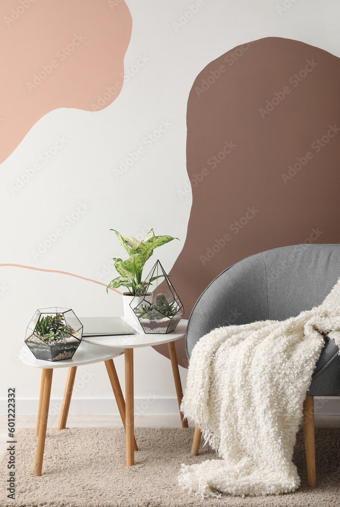 Interior of living room with florariums on tables and armchair