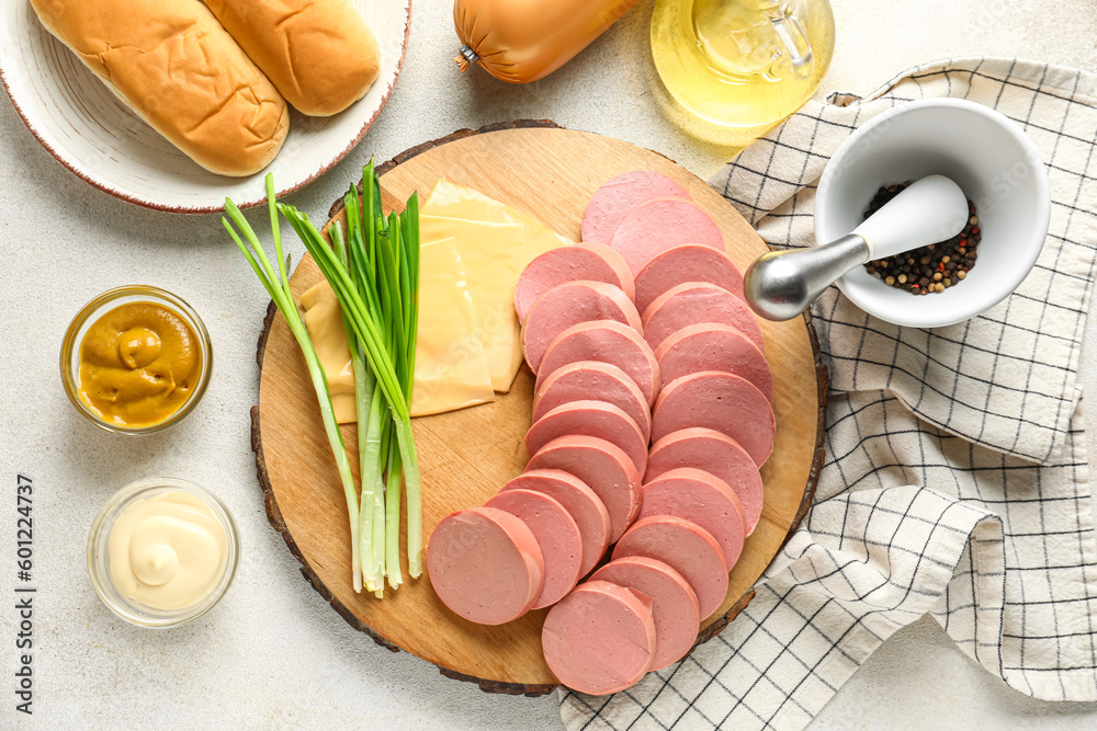 Slices of tasty boiled sausage, sauces and cheese on light background