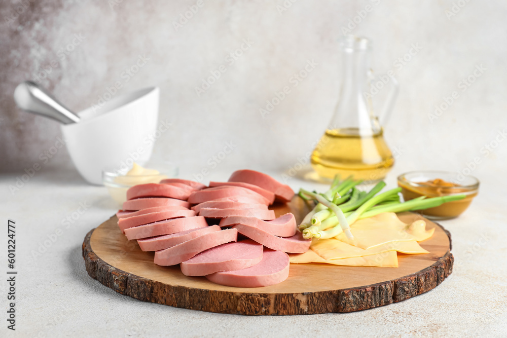 Wooden board with tasty sliced boiled sausage and cheese on light background