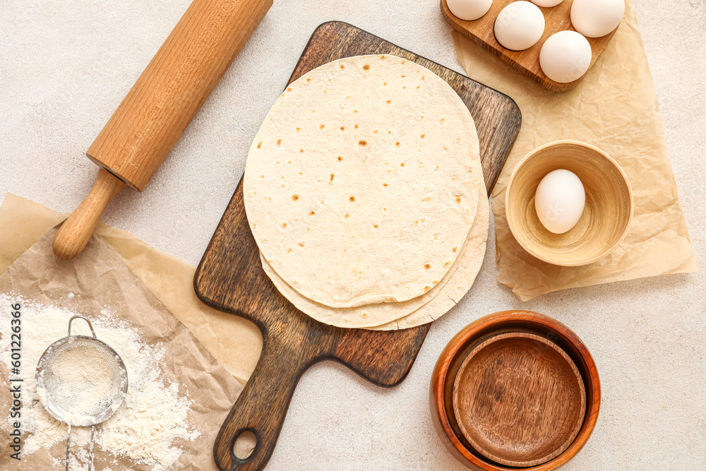 Wooden board with fresh lavash and ingredients on light background