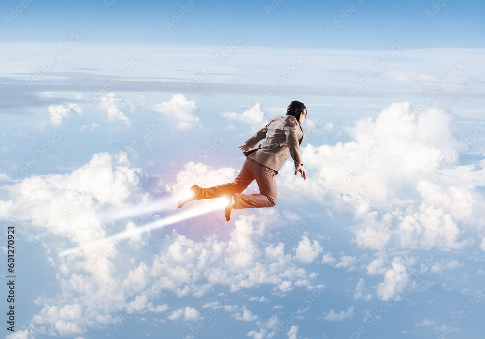 Businessman in suit and aviator hat flying in sky