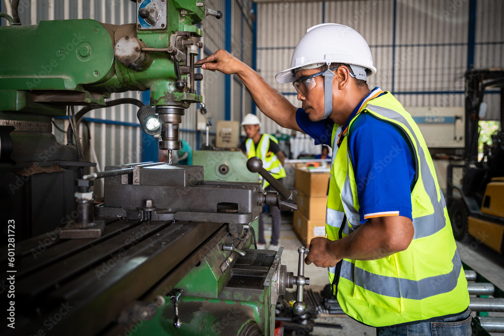 Asian worker wearing safety goggles working at lathe. Safety first concept.