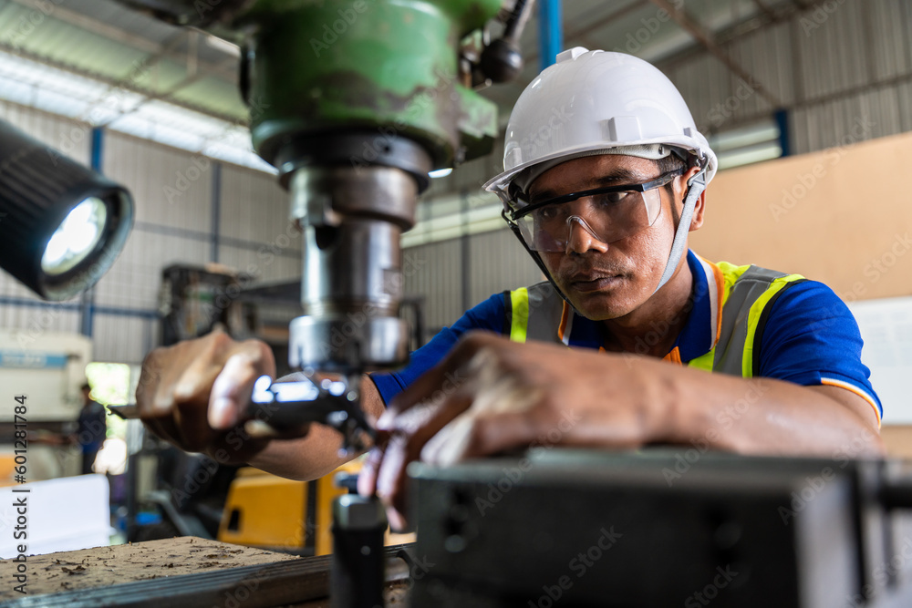 Asian worker man wearing uniform safety and hardhat uses a vernier measuring machine to inspect comp