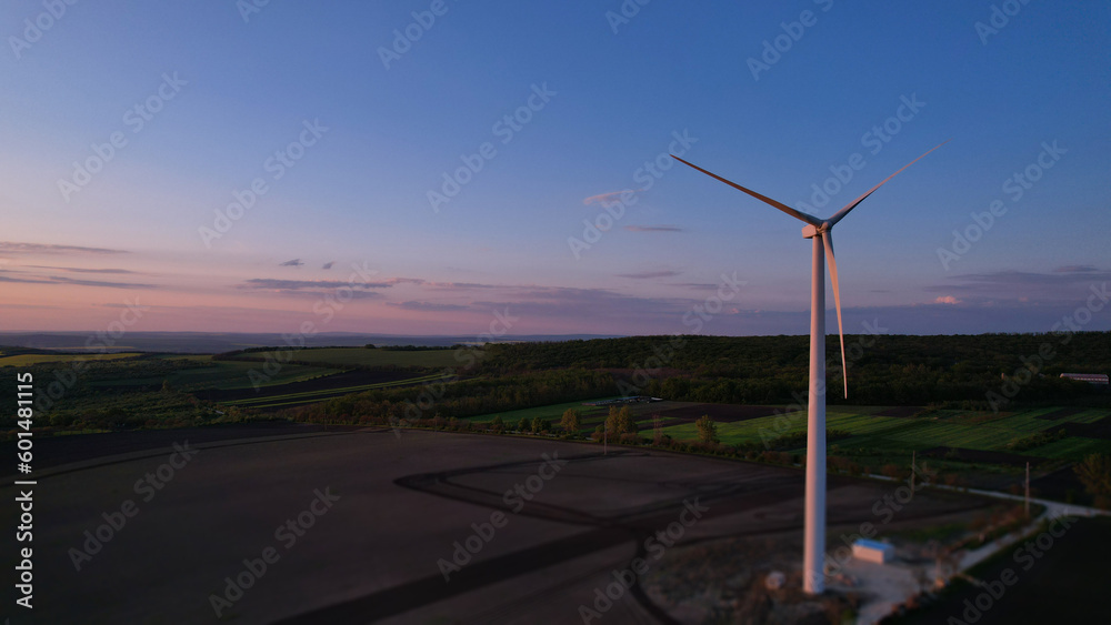 Windmill turbines generating green energy electric at sunset.