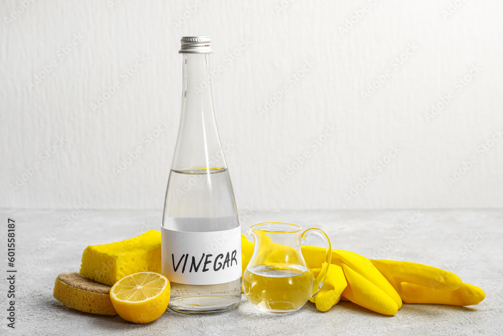 Bottle of vinegar, rubber gloves, sponges and lemon on table