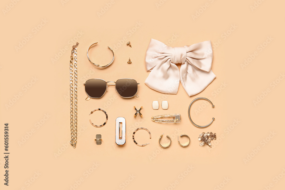 Stylish jewelry with sunglasses on beige background