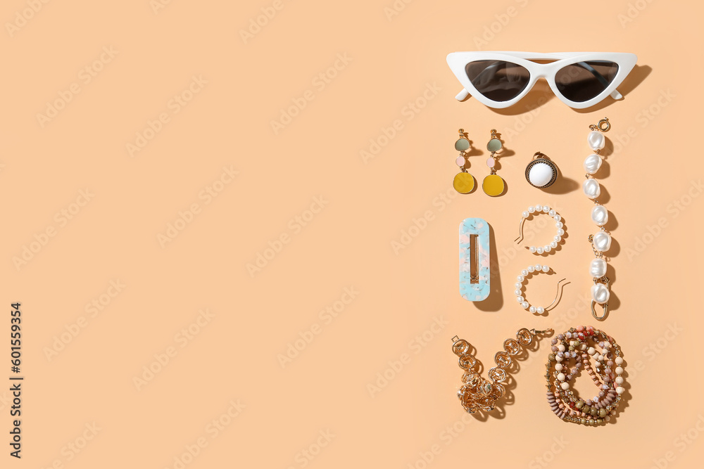 Stylish jewelry with sunglasses on beige background