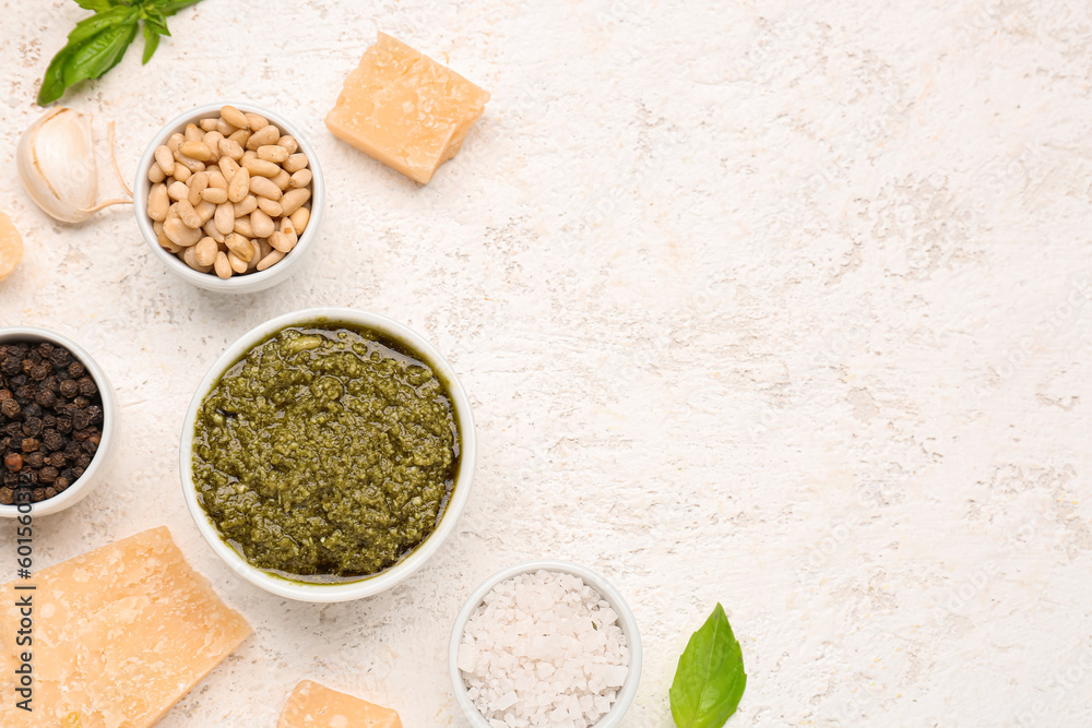 Composition with bowl of pesto sauce and ingredients on white table