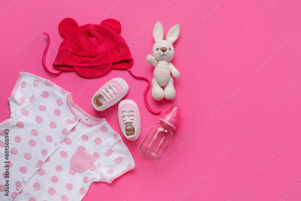 Composition with baby clothes, toy and bottle on pink background