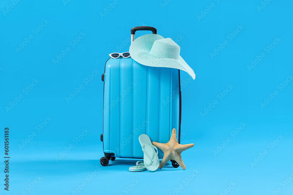 Suitcase with beach accessories on blue background