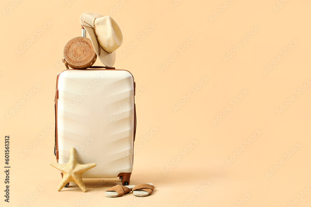 Suitcase with beach accessories on beige background