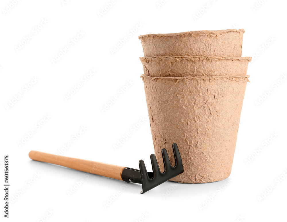 Peat pots and rake on white background