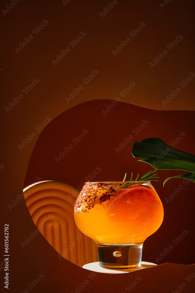 Glass of fresh summer cocktail with grapefruit and rosemary on stand visible through color paper