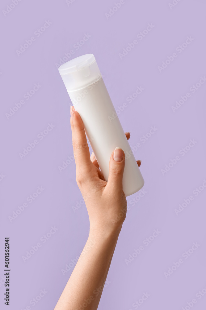 Hand holding cosmetic product on lilac background