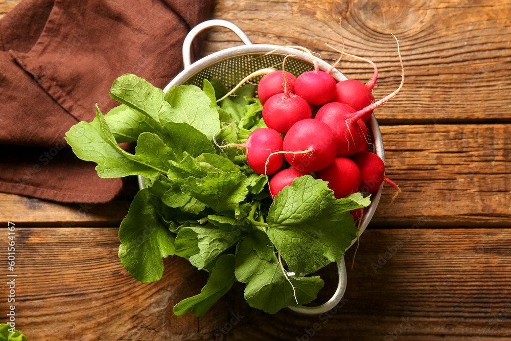 Colander with fresh radish on wooden background