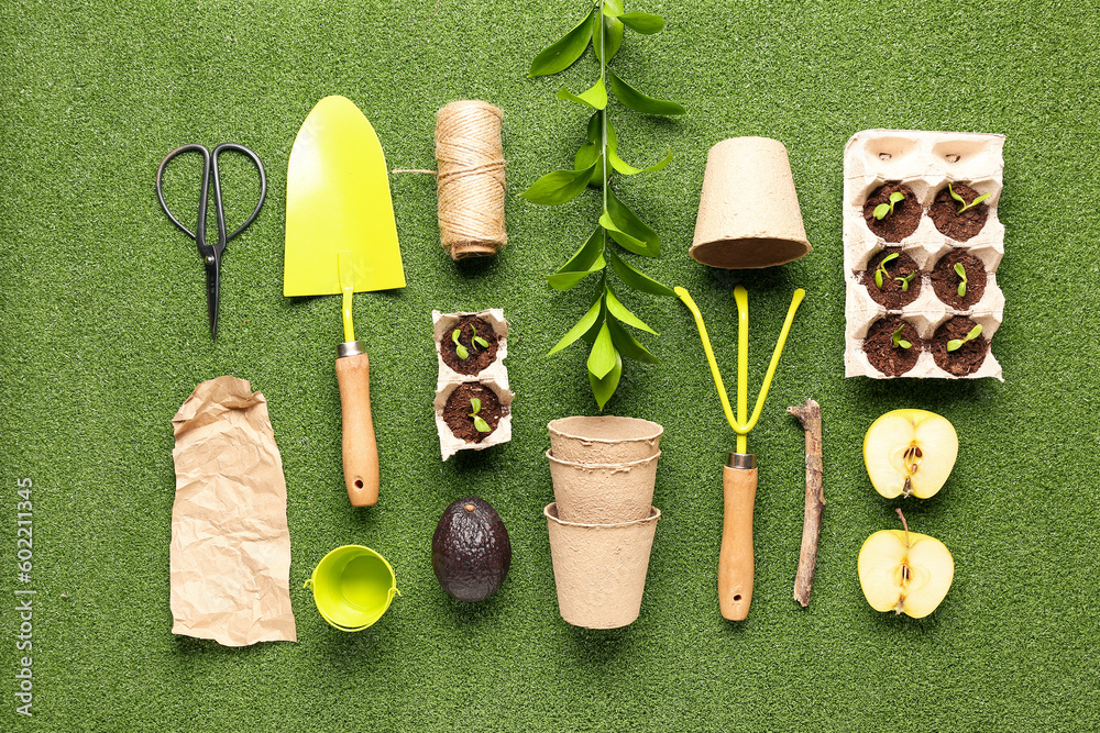 Cardboard boxes with seedlings, peat pots, fruits, and gardening tools on green background