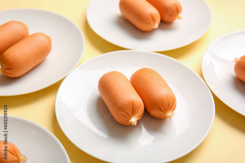 Plates of tasty boiled sausages on beige background