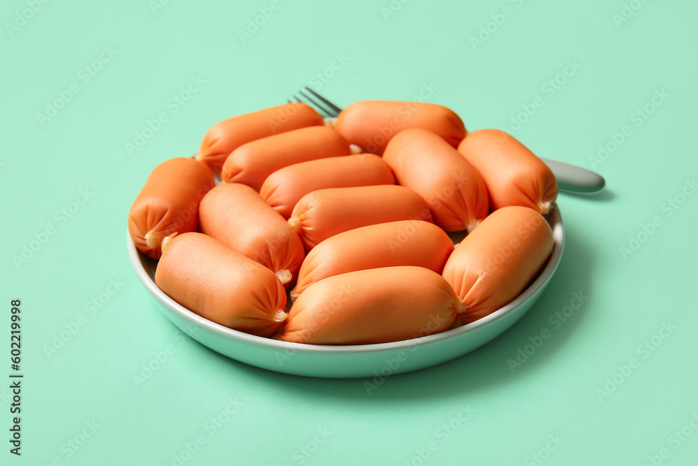 Plate of tasty boiled sausages on turquoise background