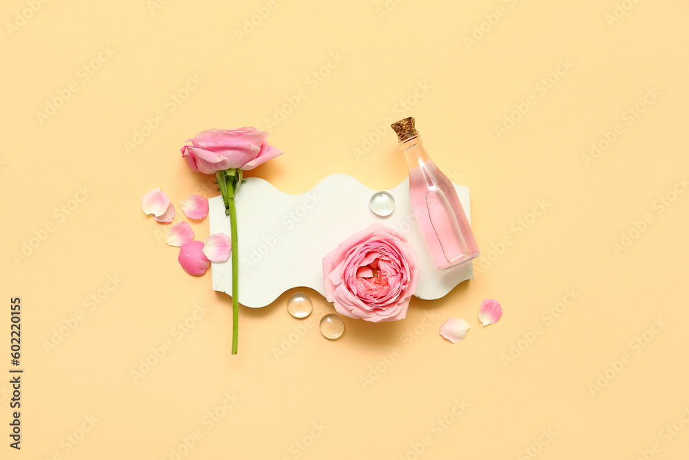 Bottle of cosmetic oil with rose extract and flowers on yellow background