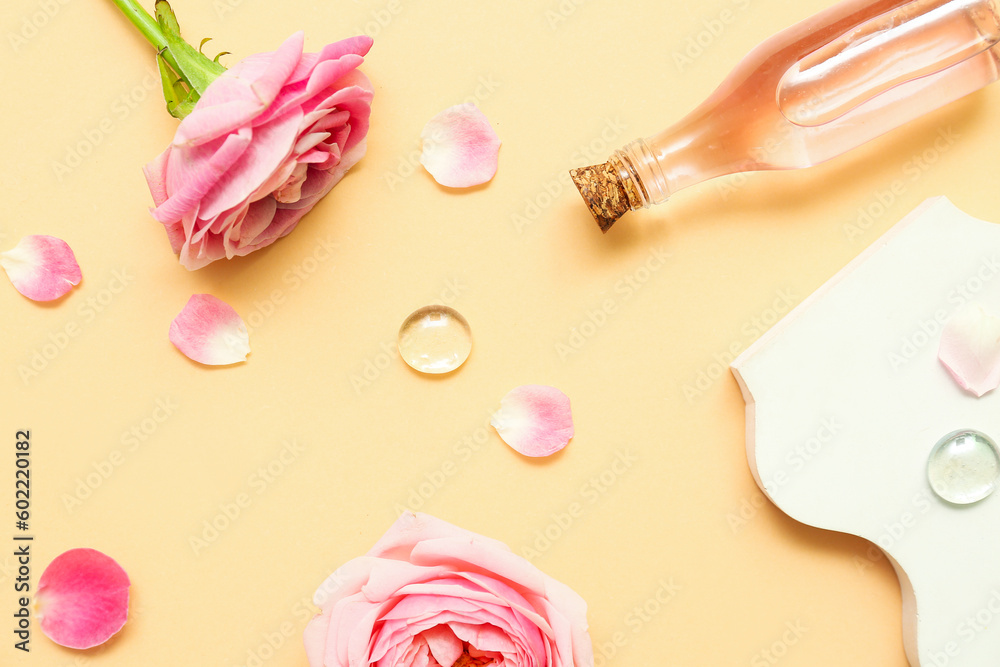 Bottle of cosmetic oil with rose extract and flowers on yellow background